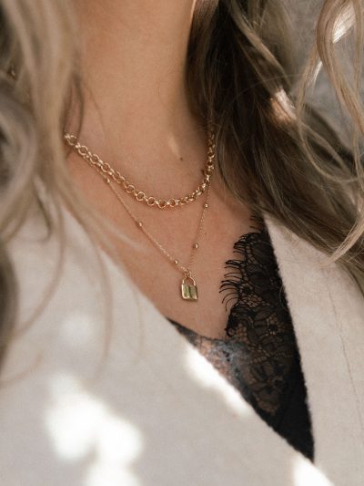 Photo lifestyle Karine avec deux colliers dorés chaîne boules avec cadenas et chaîne rollo Florence 8 et 9 automne 2024 Kara Bijoux