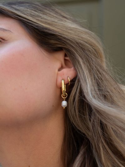 Photo lifestyle Karine avec boucles d'oreilles plaquées or anneaux ovales épais avec perle blanche suspendue Margot 9 automne 2024 Kara Bijoux